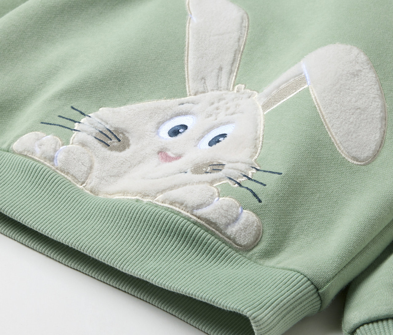 Un sweat-shirt vert clair avec une tête de lapin cousue.