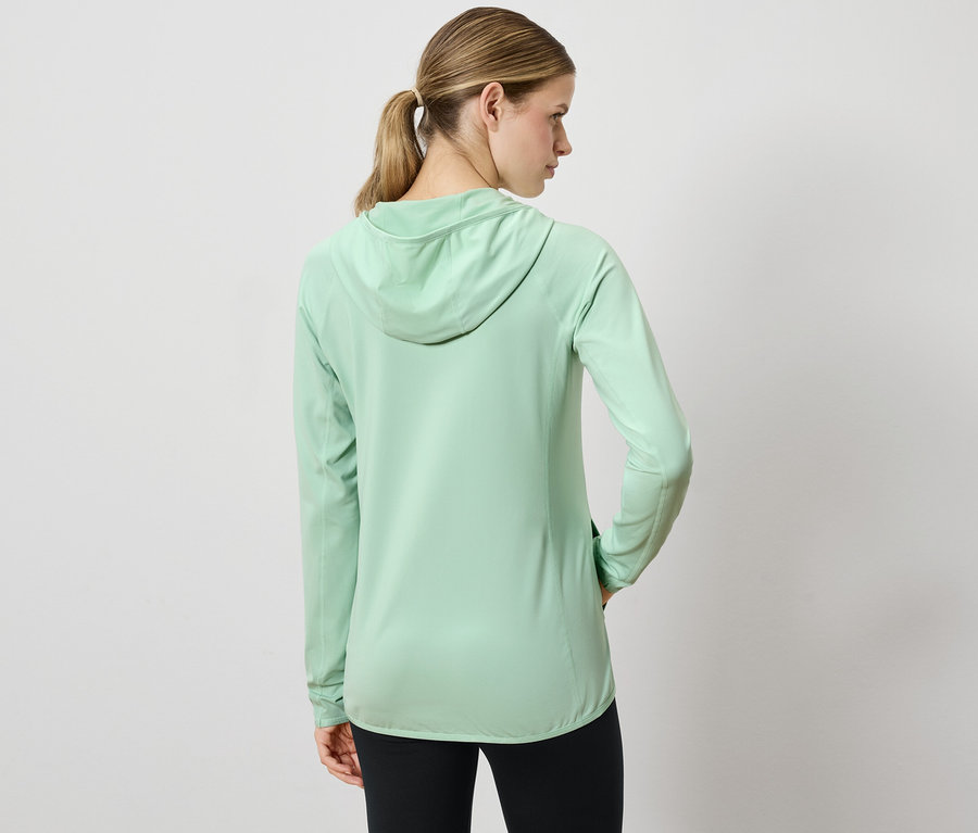 Une femme, dos à la caméra, porte un sweat à capuche vert clair et un legging noir.