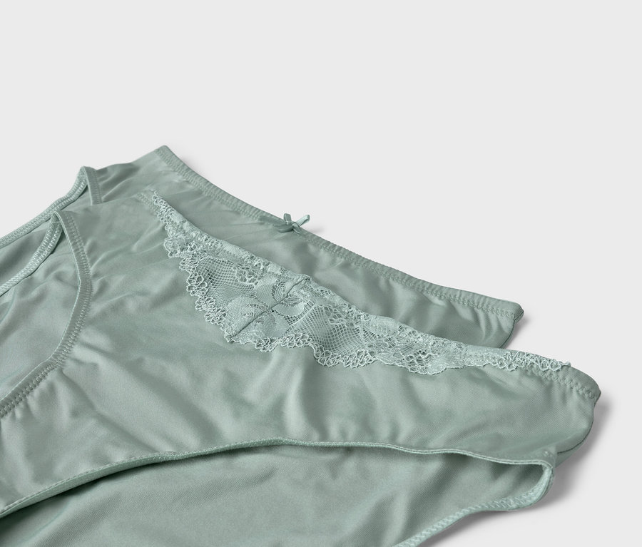Deux culottes vert clair avec de la dentelle sont posées l'une sur l'autre.