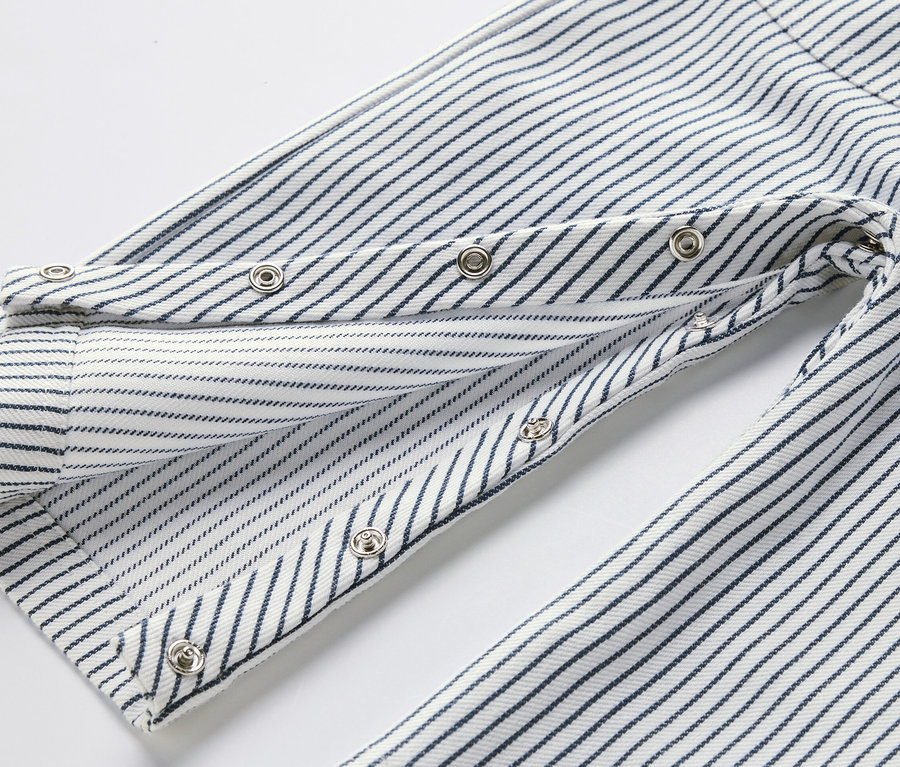 Gros plan sur une salopette tissée pour enfants avec des rayures bleues et des boutons-pression.