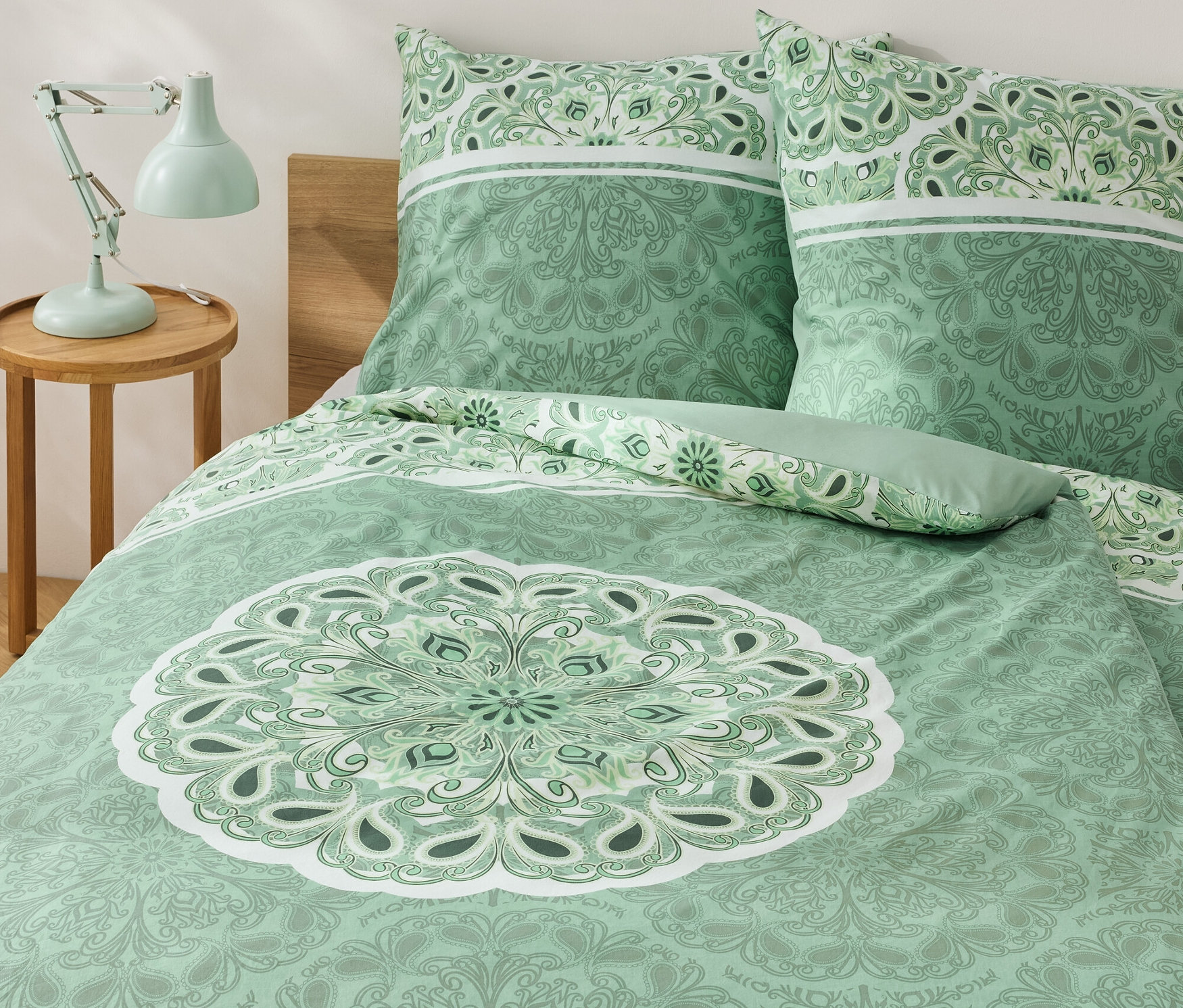 Parure de lit verte en renforcé avec un motif mandala sur un lit.