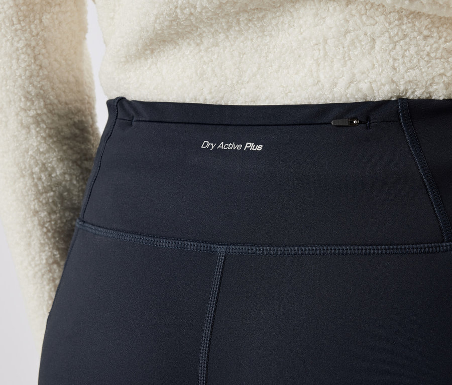 Gros plan sur un legging noir pour femme avec l'inscription "Dry Active Plus" et une poche zippée en haut.