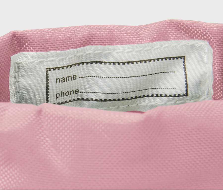 Détail de bottes en caoutchouc pour enfants avec imprimé floral intégral montrant une étiquette de nom.