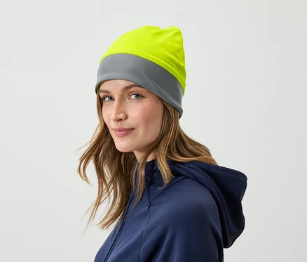 Portrait d'une femme aux cheveux bruns portant un bonnet gris et jaune et vêtue d'un sweat à capuche bleu.