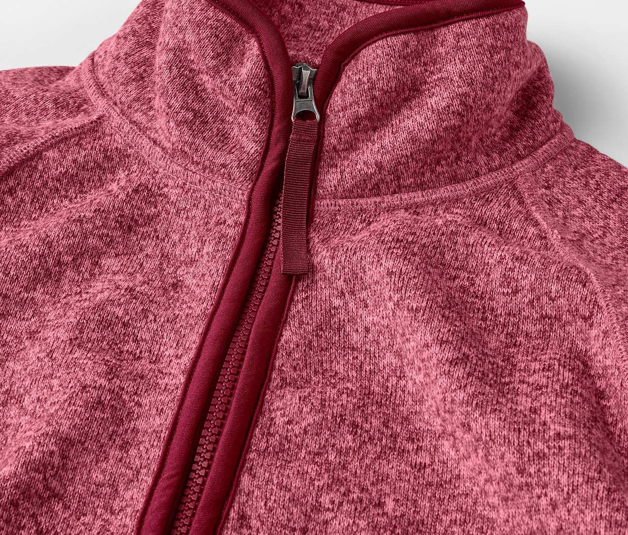 Détail d'une veste en maille polaire rose avec fermeture éclair.