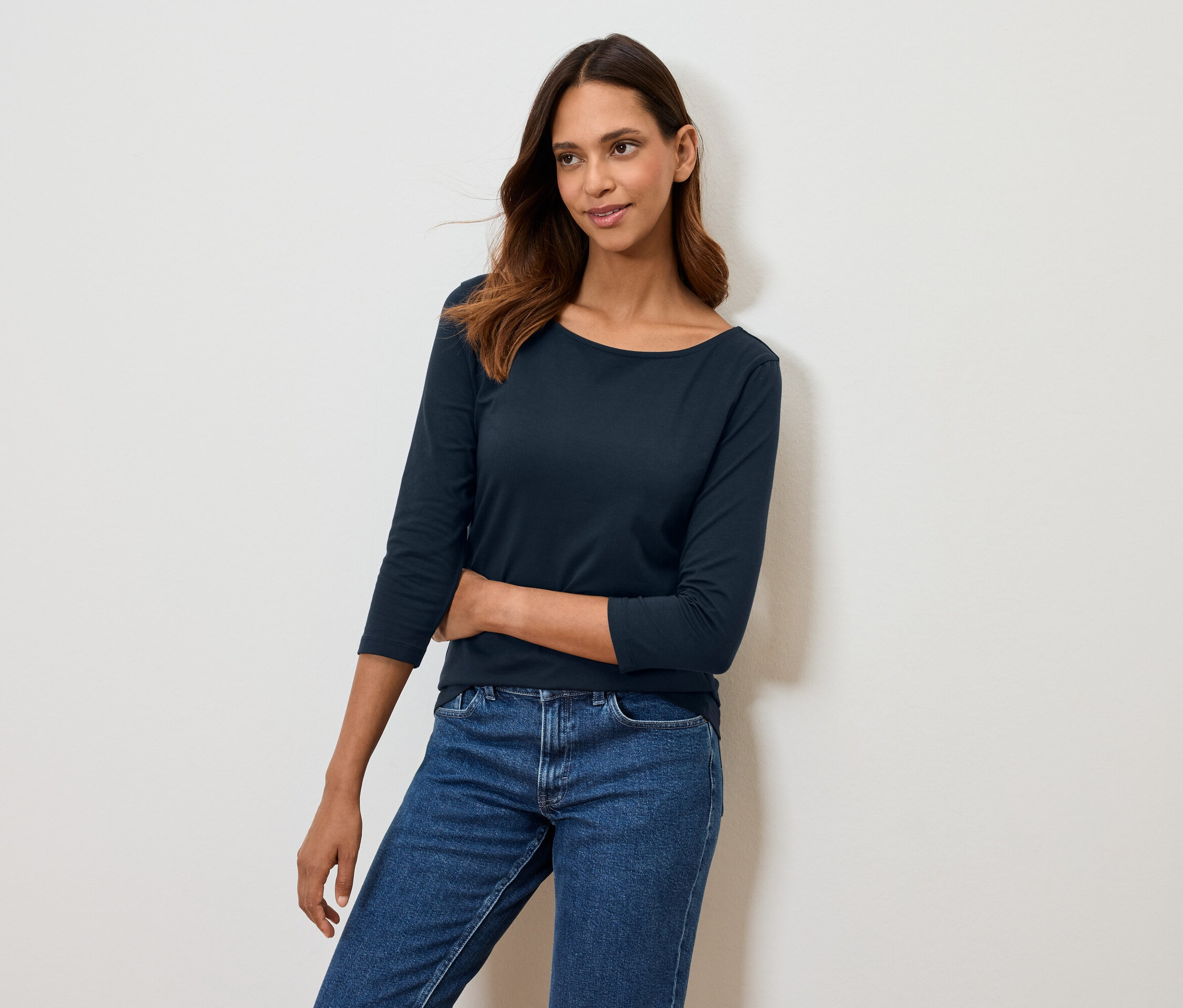 Femme posant dans un t-shirt bleu marine à manches trois-quarts et un jean bleu.