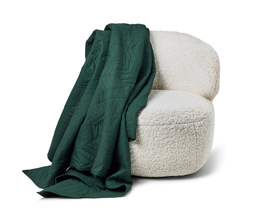 Un couvre-lit matelassé vert foncé (230 x 250 cm) est drapé sur un fauteuil blanc.