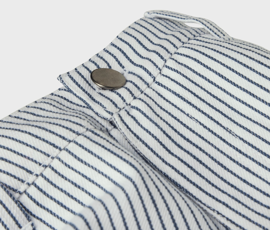 Détail d'un pantalon tissé pour enfant avec des rayures bleues et un bouton.