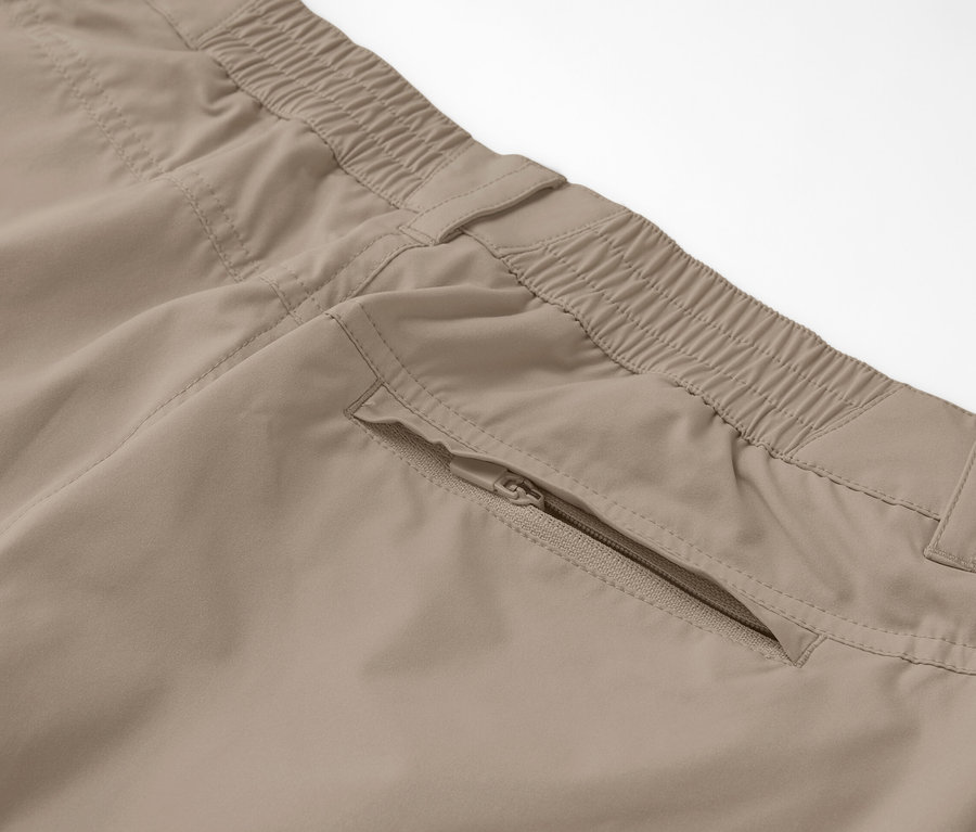 Gros plan sur un pantalon fonctionnel 2 en 1 beige avec une poche zippée.