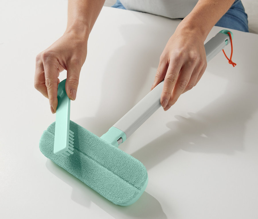 Les mains tiennent un accessoire de nettoyage pour textiles 4 en 1.