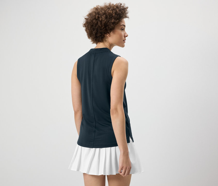 Femme vue de dos portant un top fonctionnel bleu foncé et une jupe blanche.