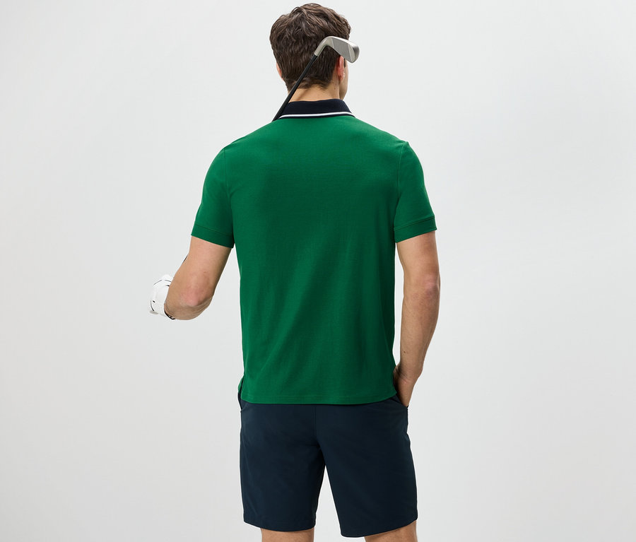 Homme vu de dos portant un polo fonctionnel vert et un short bleu marine.