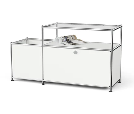 Système de rangement modulaire blanc avec cadre chromé et étagères en verre, un magazine roulé est posé sur l'étagère supérieure.