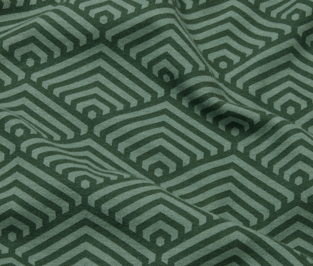 Gros plan sur deux taies d'oreiller en molleton vertes avec un motif géométrique.