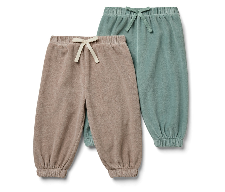 Deux pantalons de survêtement pour enfants : un beige et un vert.