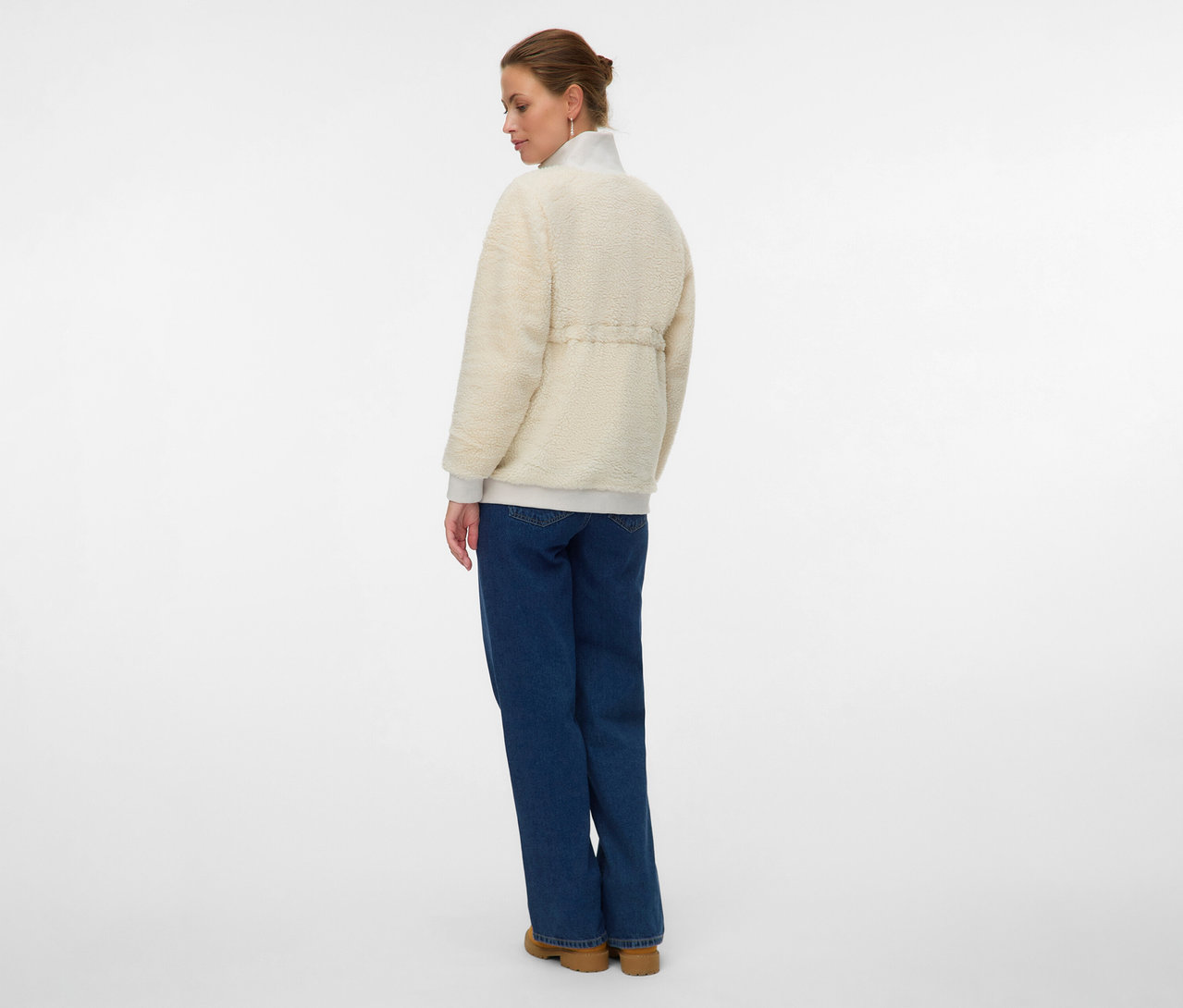 Femme de dos portant une veste Teddy 3 en 1 MAMALICIOUS «
MLCARLY », un jean et des chaussures.