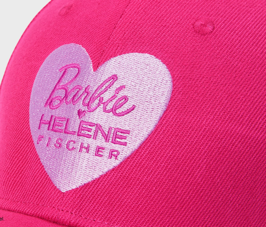 Gros plan d'une casquette rose avec un cœur rose clair brodé portant l'inscription « Barbie HELENE FISCHER ».