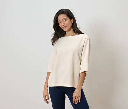 Une femme porte un haut clair et un pantalon foncé.