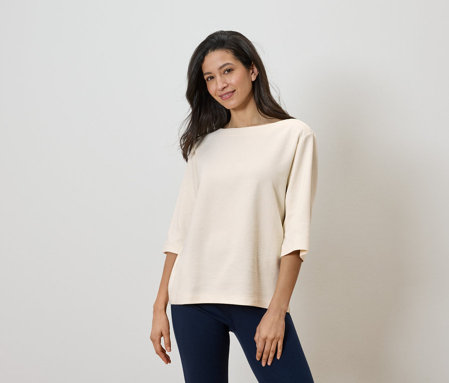 Une femme porte un haut clair et un pantalon foncé.