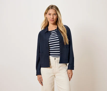 Femme portant une veste bleu marine sur un haut rayé et un pantalon crème.