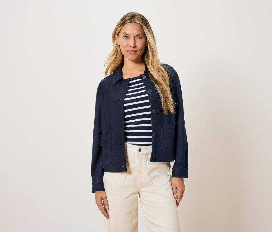 Femme portant une veste bleu marine sur un haut rayé et un pantalon crème.