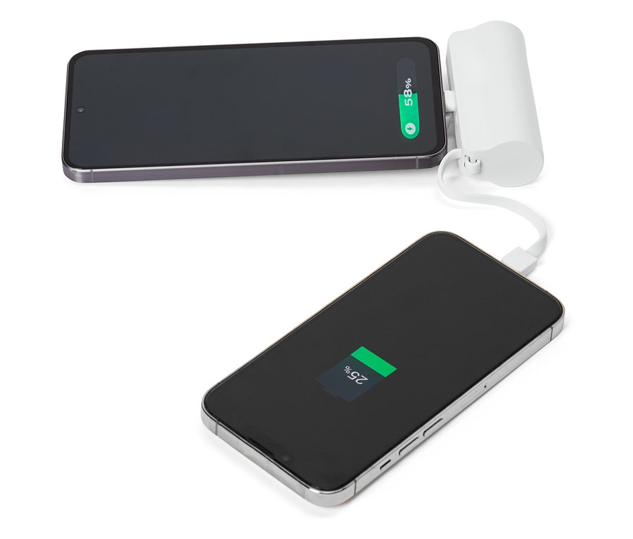 Deux smartphones, dont un connecté à un chargeur portable blanc, posés sur une surface blanche.