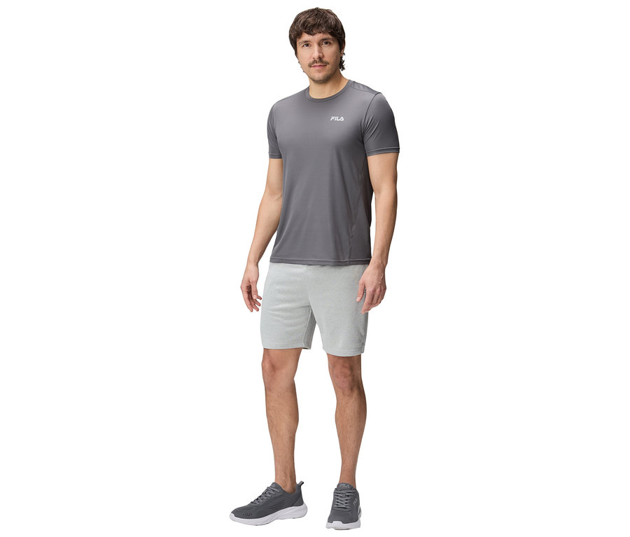 Homme en tenue de sport grise Fila, composée d'un t-shirt, d'un short et de baskets.