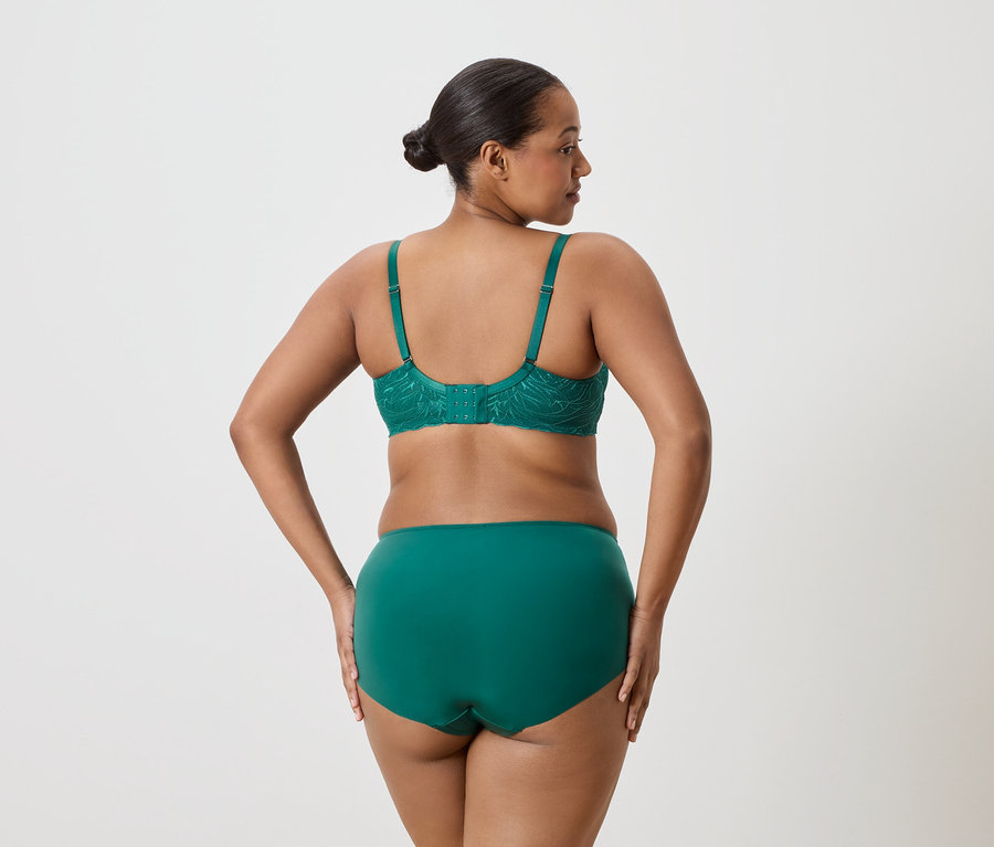 Vue arrière d'une femme portant un chignon, portant un soutien-gorge en dentelle émeraude et des sous-vêtements assortis.