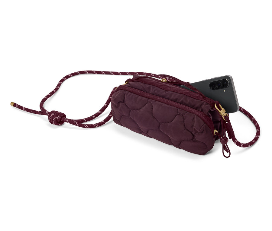 Un sac matelassé bordeaux avec une bandoulière en corde et un smartphone noir qui dépasse du sac.