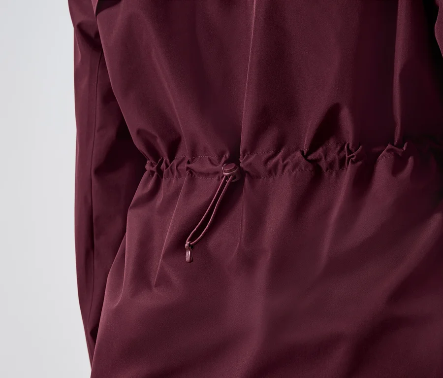 Gros plan sur une veste bordeaux avec cordon de serrage à la taille.