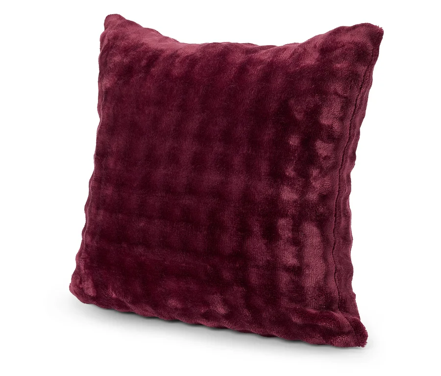 Coussin carré bordeaux avec une housse douce posé sur une surface blanche.