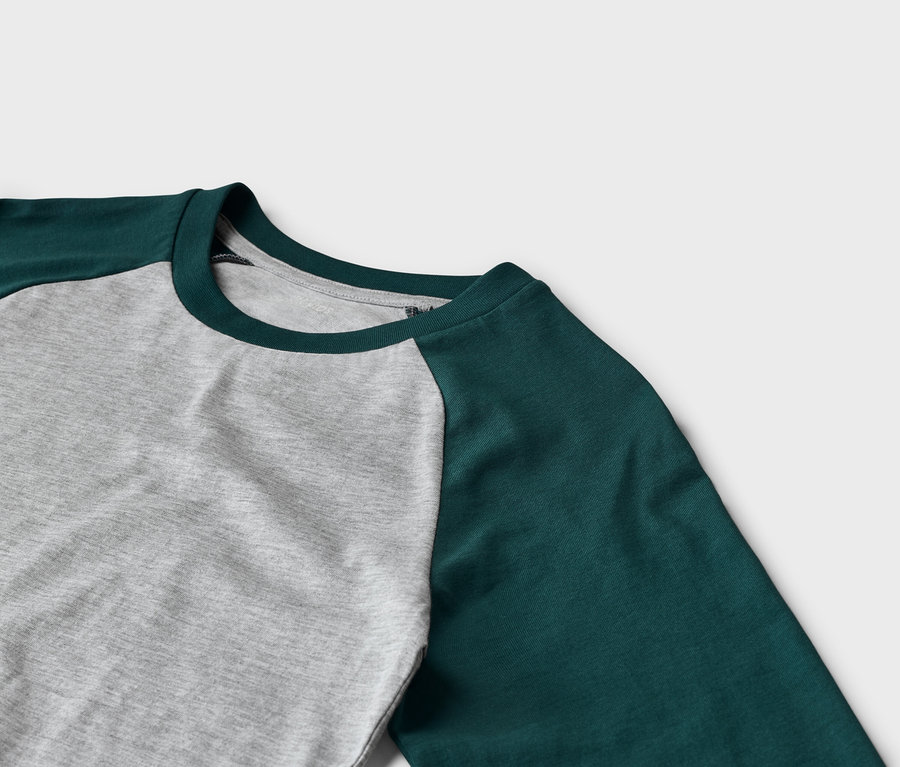 Gros plan d'un t-shirt à manches longues avec un corps gris et des manches raglan vert foncé, doté d'un col rond vert foncé.