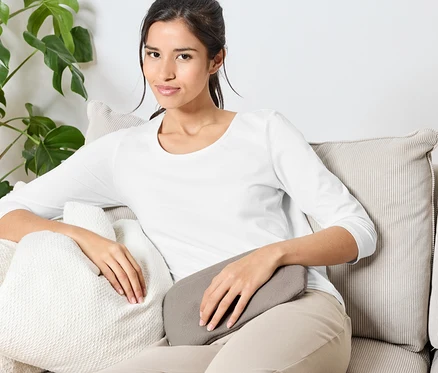 Une femme est assise sur un canapé avec des coussins.