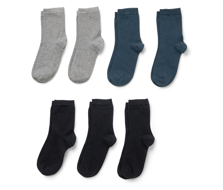 Trois paires de chaussettes en gris, bleu marine et noir sont posées sur un fond blanc.