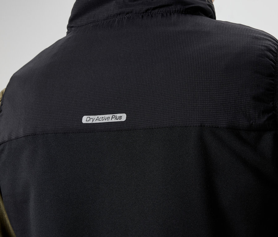 Gros plan sur l'arrière d'un gilet noir avec l'inscription "Dry Active Plus" porté sur une chemise à manches longues vert olive.