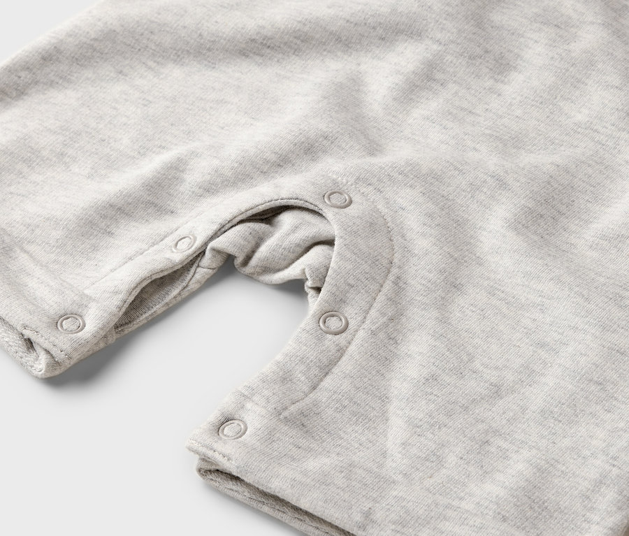 Gros plan sur une grenouillère pour bébé gris clair avec des boutons-pression.