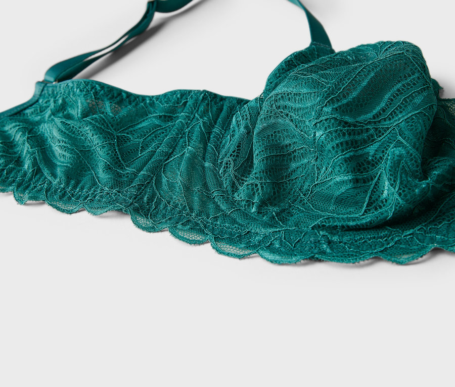Gros plan d'un soutien-gorge vert en dentelle avec des bretelles sur fond blanc.