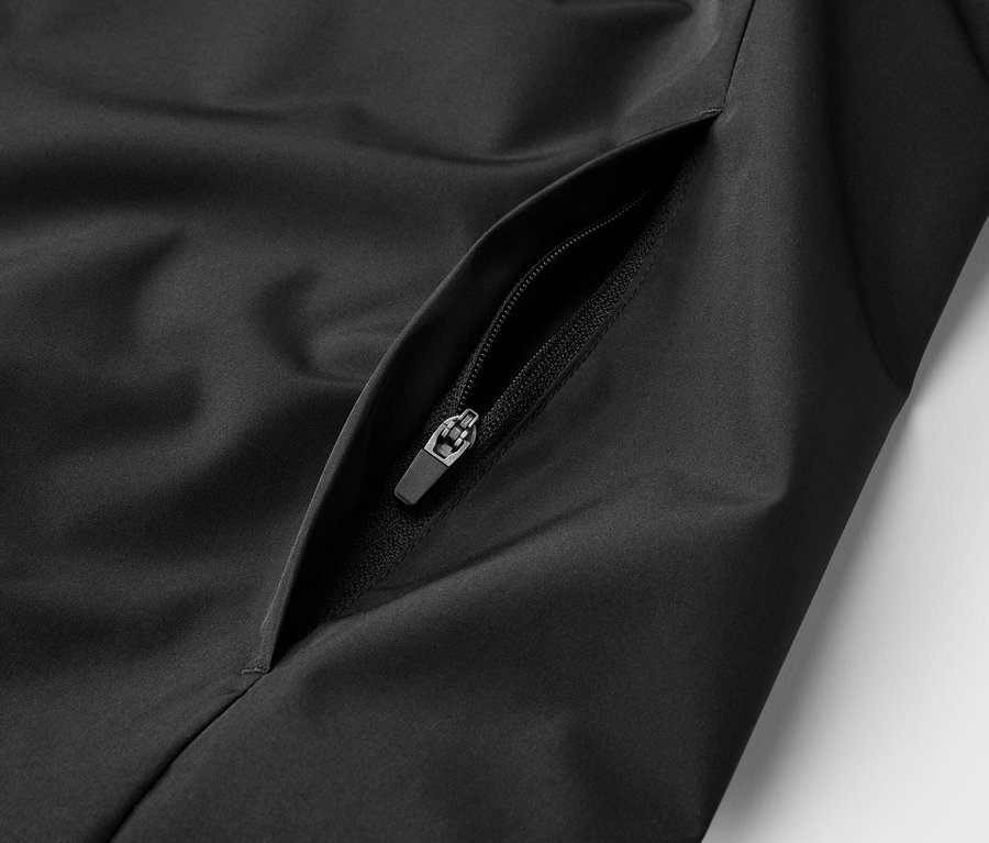 Gros plan sur une veste noire avec une poche zippée.