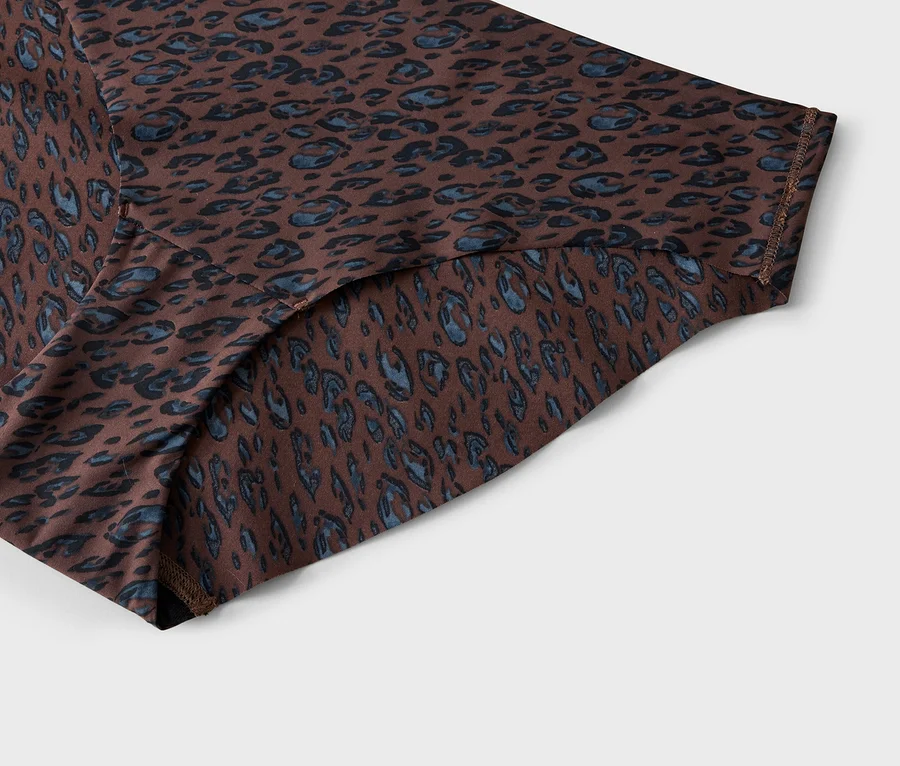 Gros plan d'un tissu marron avec un motif léopard bleu et noir, montrant des coutures visibles sur les bords.
