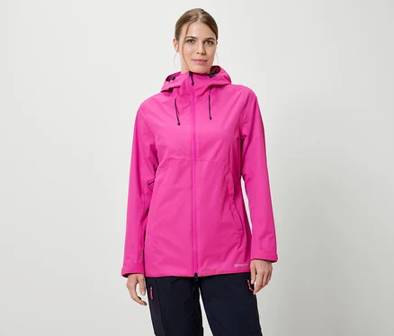 Une femme portant une veste de pluie rose à capuche et un pantalon bleu marine sur un fond blanc.