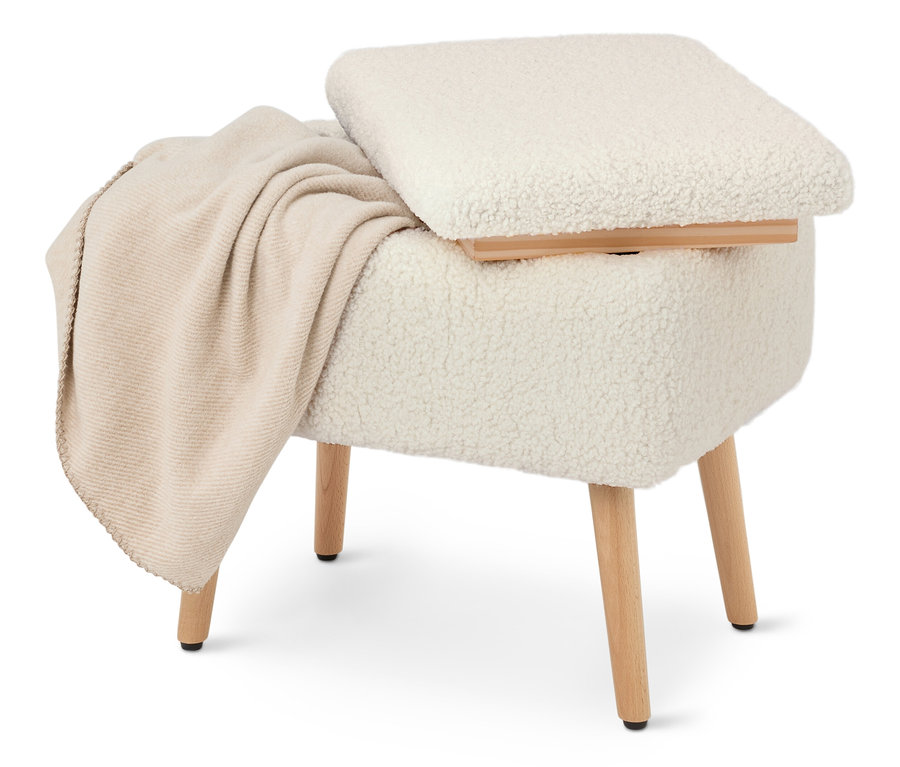 Un tabouret crème recouvert de tissu type teddy avec des pieds en bois et une couverture beige posée dessus.