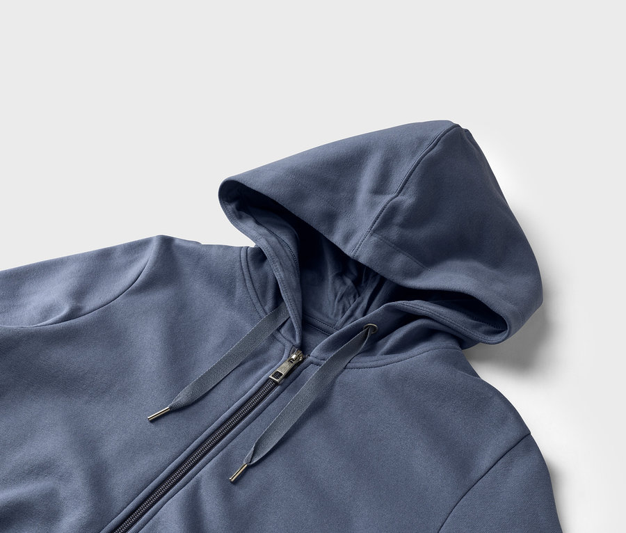 Gros plan d'un sweat à capuche bleu avec fermeture éclair sur fond blanc.