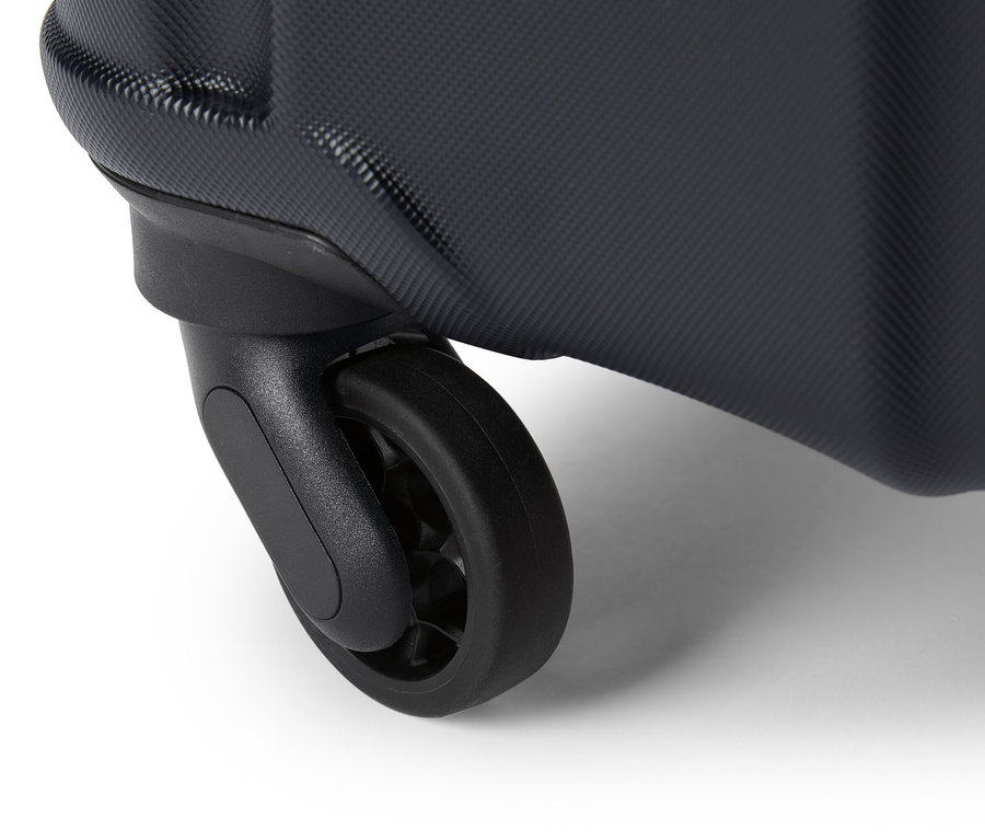 Gros plan d'une roue de valise noire sur un fond blanc.