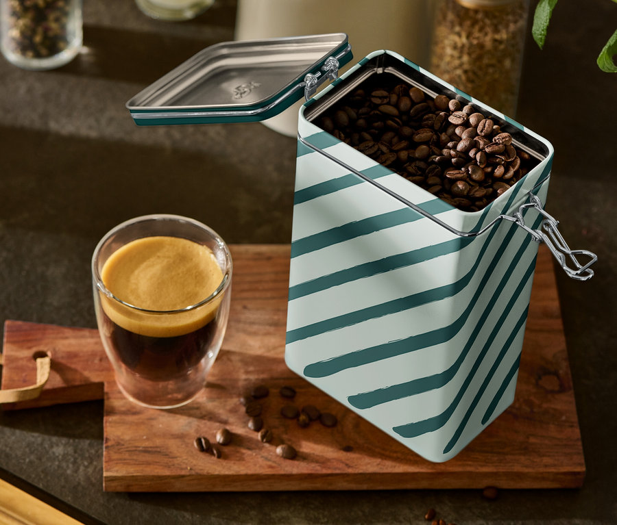 Un verre d'espresso et une boîte à café rayée ouverte sont posés sur une planche en bois.