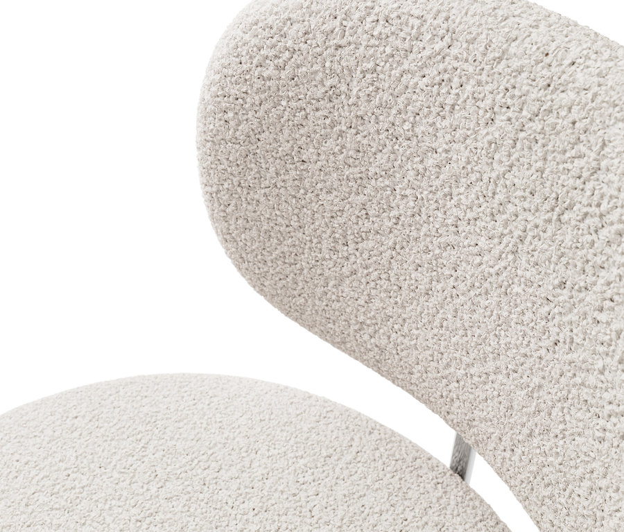 Gros plan du dossier et de l'assise d'un fauteuil en tissu bouclé crème.