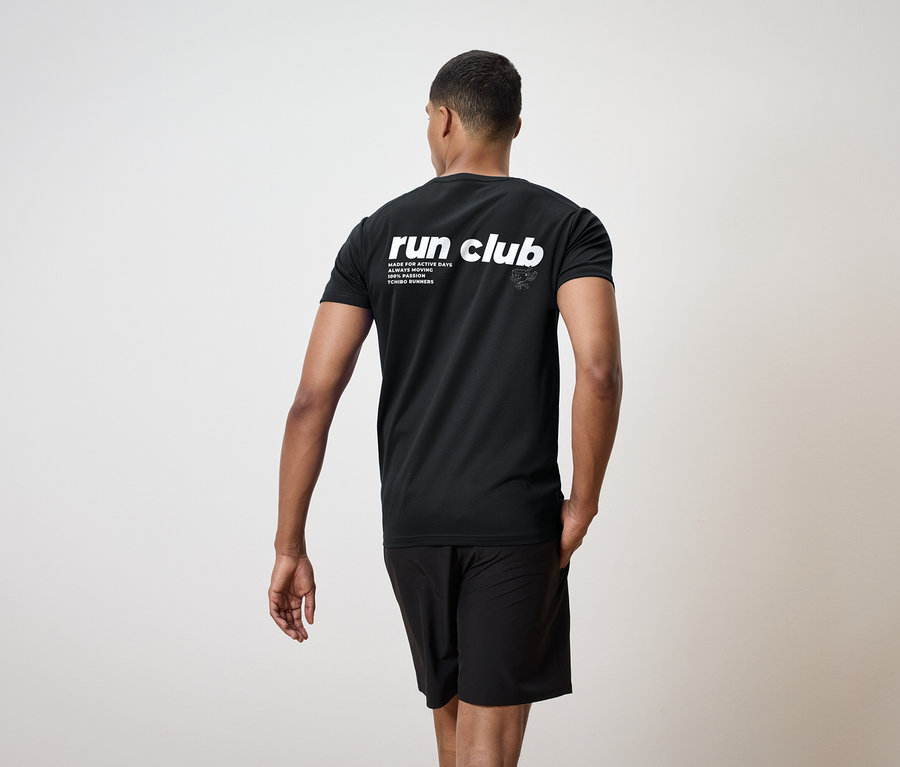 Un homme vu de dos, portant un t-shirt noir avec l'inscription "run club" et un short noir.