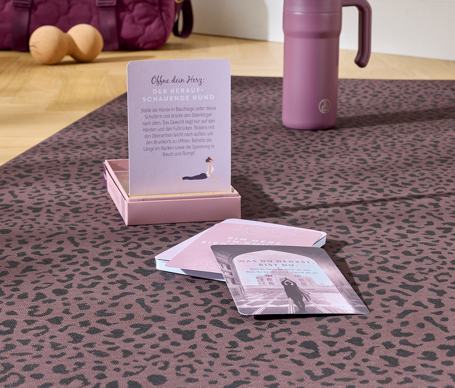 Sur un tapis à motifs se trouvent des cartes de yoga, une bouteille d'eau et un sac en arrière-plan.