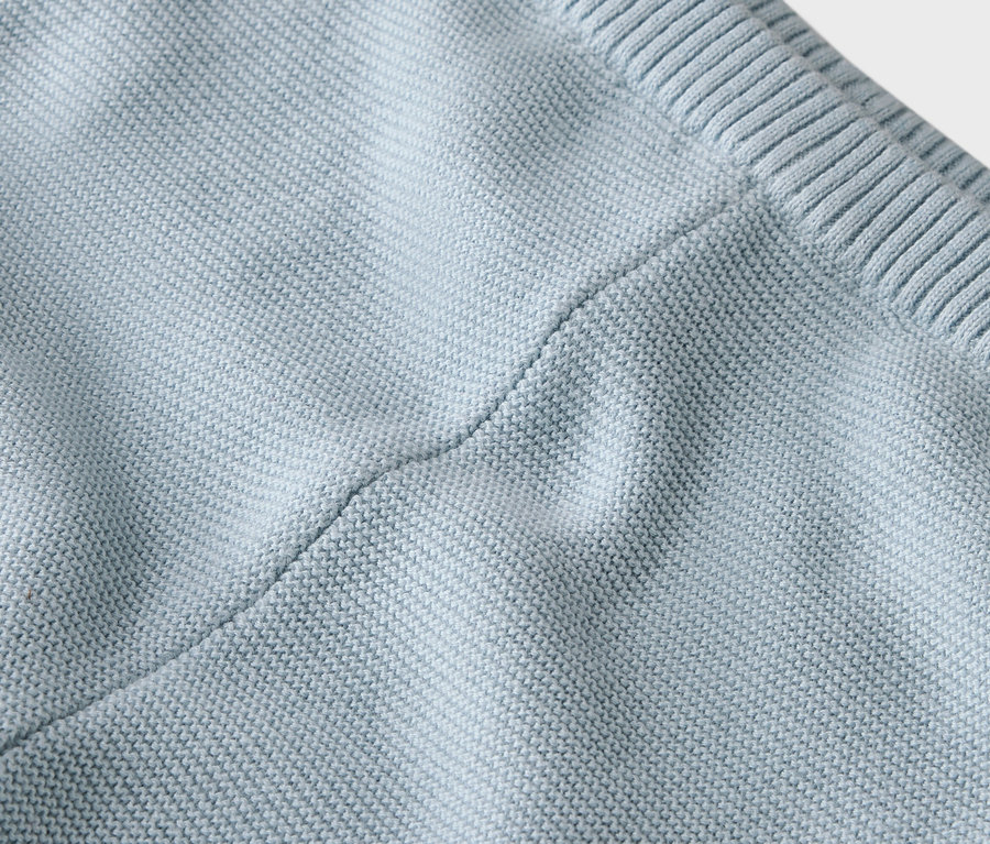 Gros plan d'un tissu tricoté bleu clair avec une couture.