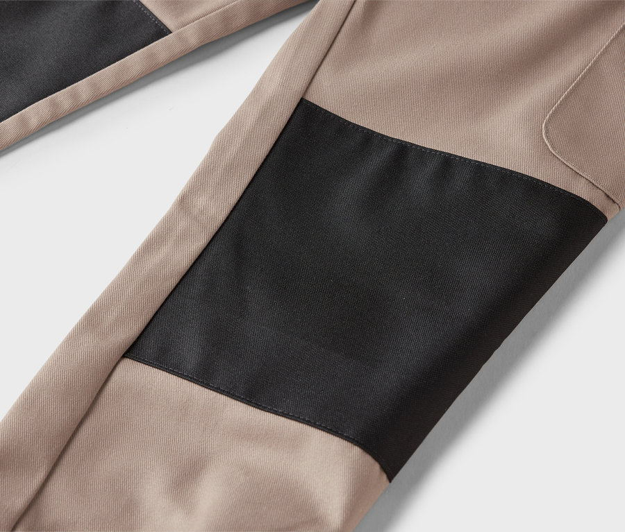 Gros plan sur un pantalon beige avec des empiècements noirs.