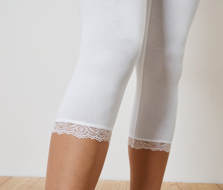 Gros plan sur des jambes portant des leggings blancs arrivant aux genoux avec une bordure en dentelle.
